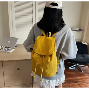 Bright yellow canvas drawstring backpack worn by model in a modern home office setting