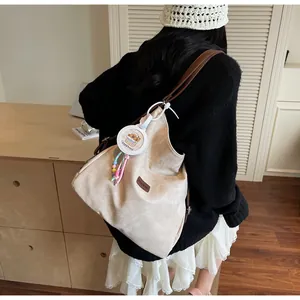 Detail of beige corduroy tote with brown leather straps and a cute capybara charm