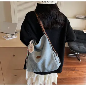 Close-up of light blue canvas tote bag with brown leather straps and a decorative charm