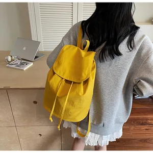 Detailed back view of a bright yellow canvas drawstring backpack worn for leisure style