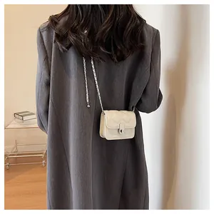 Model wearing a cream quilted crossbody bag with silver chain and metal clasp