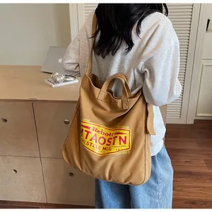 Detail of caramel canvas tote bag with retro vintage logo and dual handle straps