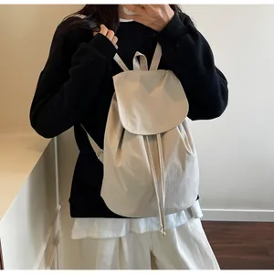 Detail of minimalist cream drawstring backpack featuring a canvas fold-over flap design