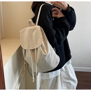 Close-up detail of beige canvas backpack featuring drawstring closure and flap cover buckle