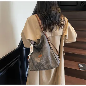 Detail view of large charcoal canvas tote bag with brown leather strap and brand tag