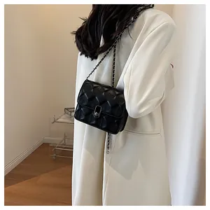 Model wearing black quilted crossbody bag with metal chain strap and silver twist lock