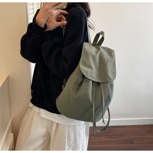 Detail of dark green drawstring backpack showing soft nylon texture and casual style