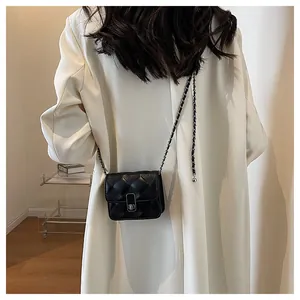 Rear view of model wearing a black quilted leather chain bag with a silver turn-lock clasp