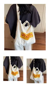 Detail showing white canvas tote bag with vintage letter print and dual handle straps