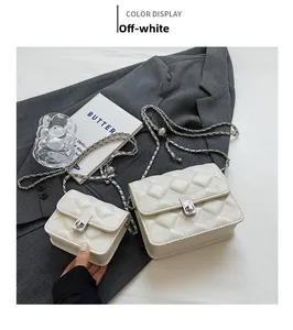 Detail view of beige quilted chain bags set on grey fabric with elegant accessories