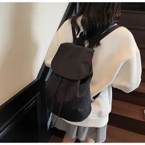 Detail view of the black nylon drawstring backpack shown on a model in a modern staircase