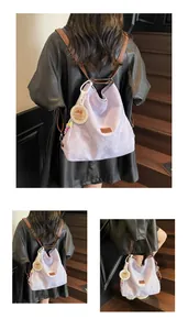 Detail view of light purple canvas backpack with leather straps and a cute capybara pendant