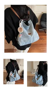 Detail of light blue canvas tote bag with brown leather straps and cute capybara charm