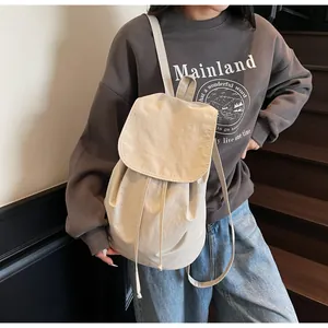 Detail view of cream canvas drawstring backpack on model, showcasing large capacity and style
