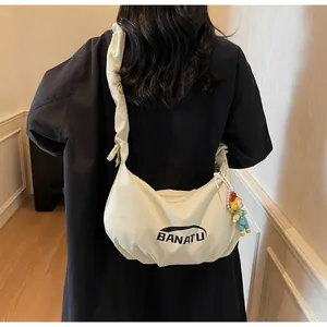 Detail of cream crossbody bag with ruffled strap and a cute character pendant charm