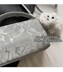 Detalle de bolso Boston plateado con textura ondulada y un lindo colgante de perro de peluche