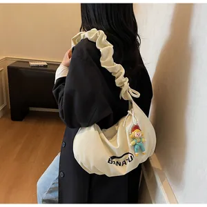 Detail of off-white crossbody bag featuring a pleated cloud strap and cartoon charm