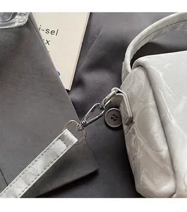 Detalle del gancho de metal plateado y el cuero gris texturizado en el bolso Boston