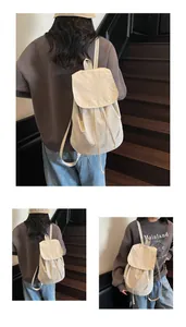 Detailed view of cream canvas drawstring backpack with minimalist flap and strap details