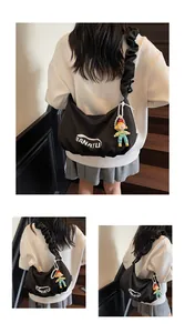 Detail of black square crossbody bag with ruched strap and cute cartoon doll pendant