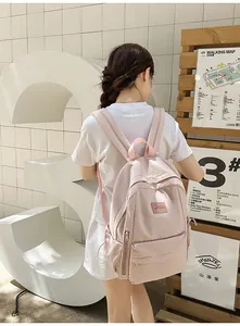 Outdoor shot of light pink minimalist backpack featuring side pockets and zipper detail