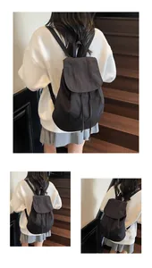 Detail view of the black canvas backpack featuring a secure drawstring closure and flap cover