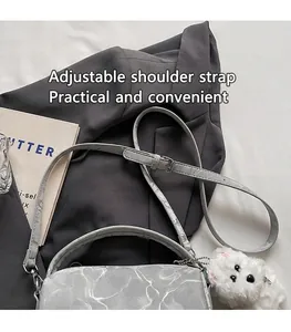 Detalle de la correa ajustable con hebilla metálica en el bolso boston gris