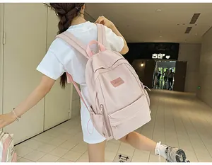 Rear view of model wearing a light pink minimalist nylon backpack with side water bottle pockets