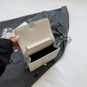 Chic quilted beige underarm chain bag with silver buckle on a stylish grey blazer