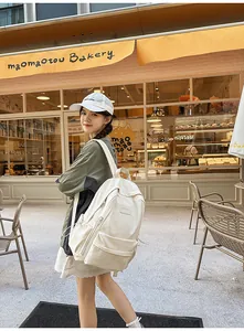 Close-up of a cream multipurpose backpack with multiple pockets in an urban street setting