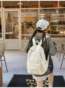 Rear view of minimalist cream white canvas backpack worn in a cozy street setting