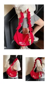Detail of red crescent shoulder bag with ruffle strap and cute doll pendant decoration