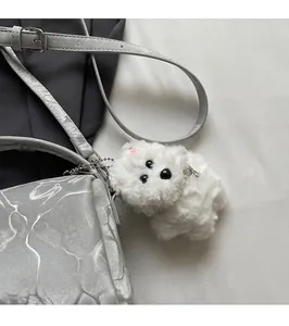 Detalle del colgante de cachorro de peluche blanco en un bolso bandolera tipo Boston