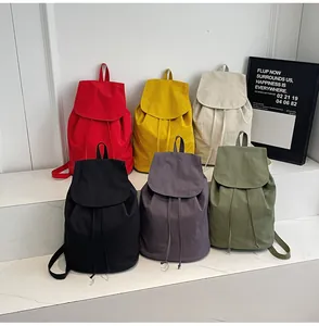 Various colors of canvas drawstring backpacks displayed on marble steps in a bright setting