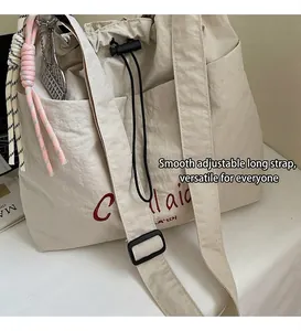 Detail view of the cream nylon tote with red embroidery and a black drawstring closure