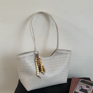 Détail du tissage en V et du gland en perles de bois sur ce sac fourre-tout tissé beige