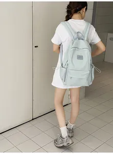 Close-up of light blue minimalist backpack with adjustable straps on a model