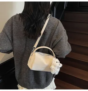 Detalle de bolso Boston crema con textura en relieve y adorno de perrito de peluche