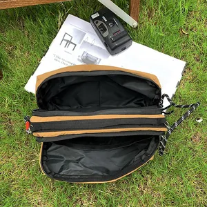 Khaki nylon crossbody bag with multi-layer zippers on a grassy outdoor background