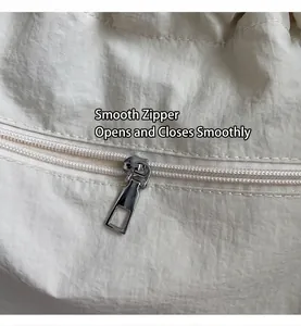 Detail of silver smooth metal zipper on off-white embroidered nylon tote bag texture