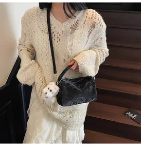 Detalle de bolso Boston negro con textura de mármol y colgante de perro de peluche