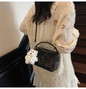 Detalle de bolso Boston negro grabado con herrajes plateados y colgante de perrito de peluche