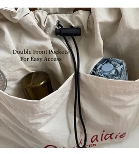 Detail of off-white drawstring tote bag featuring two front pockets with a folded umbrella