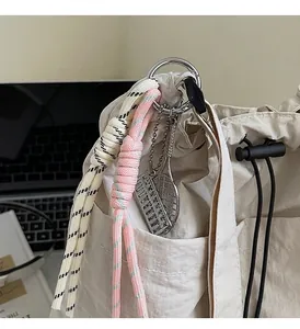 Detail of drawstring bag featuring decorative woven straps and metal sport charms