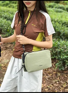 Close-up of light green nylon crossbody bag with adjustable black cord strap outdoors