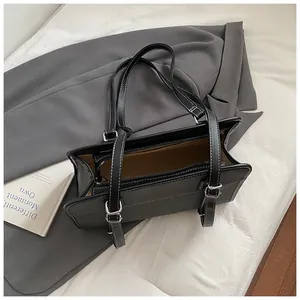 Large black shoulder bag with white contrast stitching and adjustable dual straps