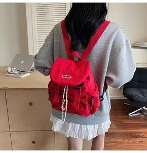 Détail du sac à dos rouge avec rabat à boucles et fermeture par cordon de serrage