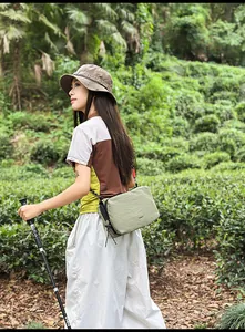 Detail of light green nylon crossbody bag with crinkle texture in outdoor forest setting
