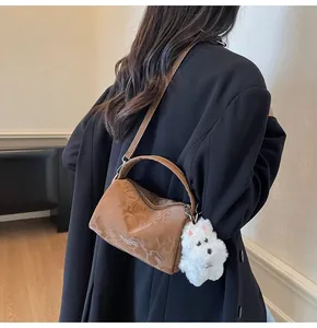 Bolso Boston marrón con textura de mármol y colgante de perrito blanco en una modelo