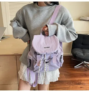 Détail du sac à dos en nylon violet avec rabat, cordon de serrage et étiquette de marque